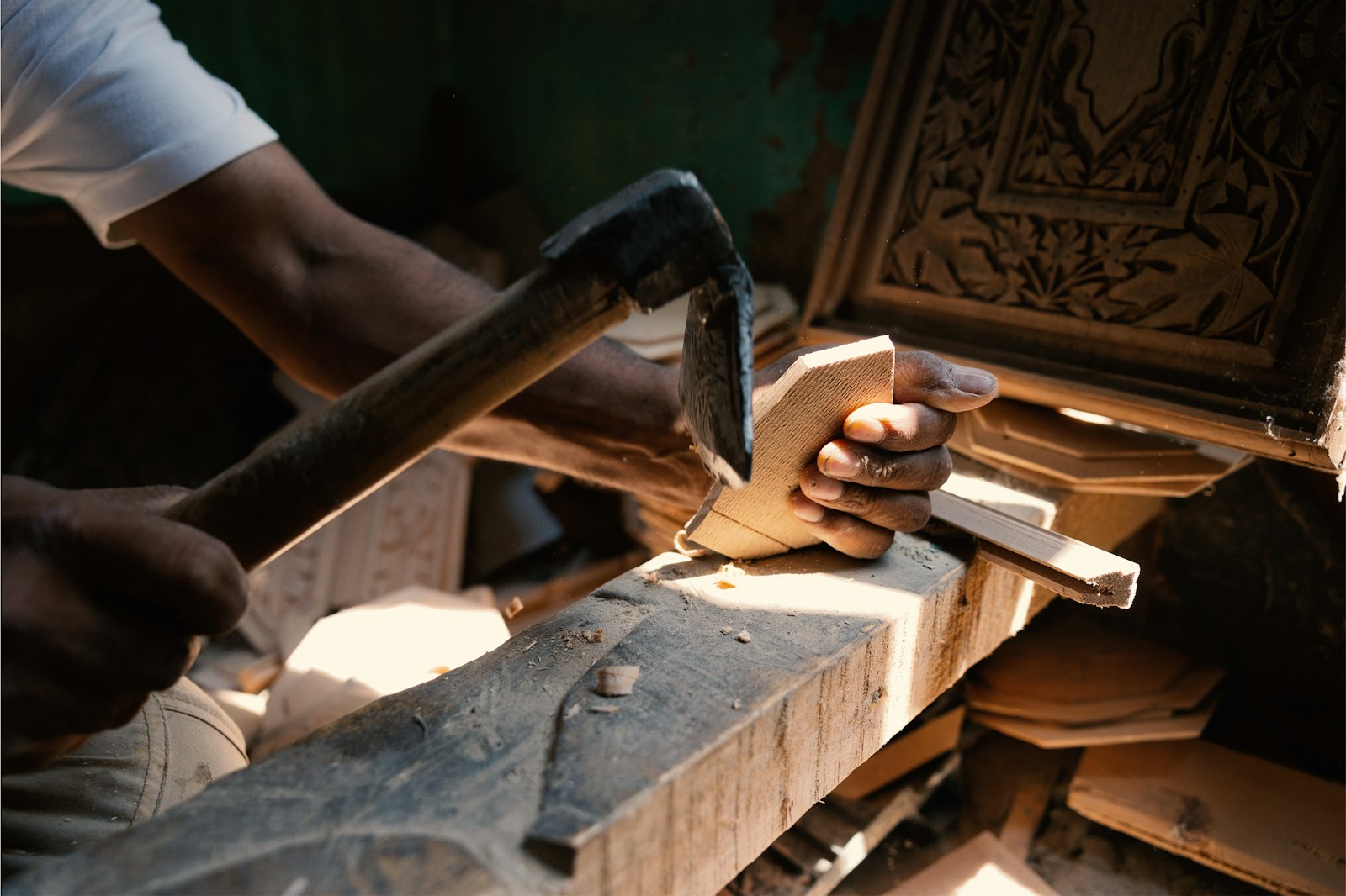A carpenter shaping a piece of timber with a hammer and chisel